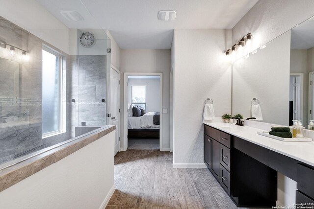 bathroom with vanity, connected bathroom, baseboards, walk in shower, and wood finished floors