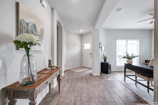 entryway with wood finished floors, visible vents, ceiling fan, and arched walkways