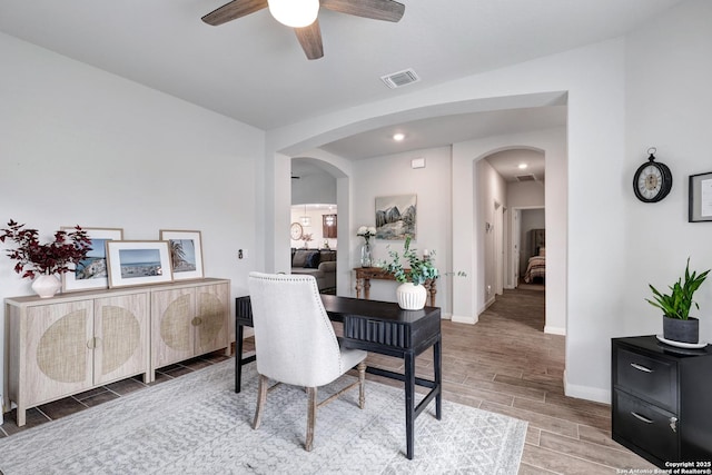 office featuring wood tiled floor, arched walkways, visible vents, and a ceiling fan