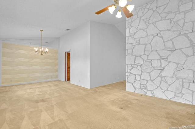 empty room with baseboards, ceiling fan with notable chandelier, carpet floors, and vaulted ceiling