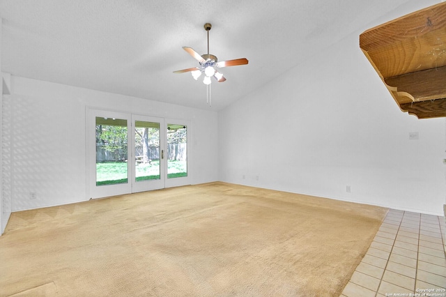 empty room featuring a ceiling fan, light tile patterned floors, light carpet, and lofted ceiling