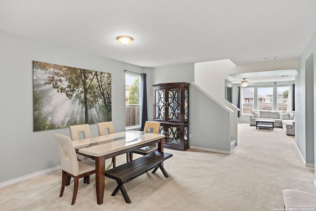 dining space featuring baseboards, stairway, a ceiling fan, and light carpet