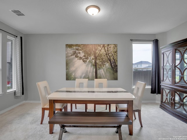 dining room with baseboards, visible vents, light carpet, and a textured ceiling