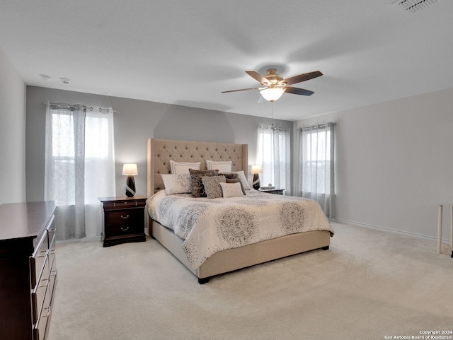 bedroom featuring ceiling fan, baseboards, visible vents, and light carpet