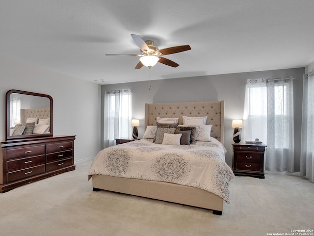 bedroom with a ceiling fan and light colored carpet