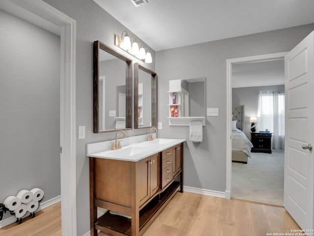 full bath with double vanity, wood finished floors, and a sink