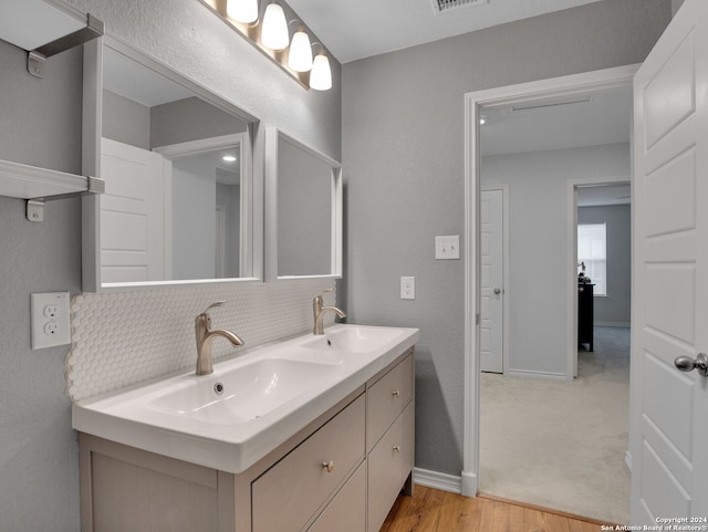 bathroom featuring double vanity, a sink, wood finished floors, and baseboards