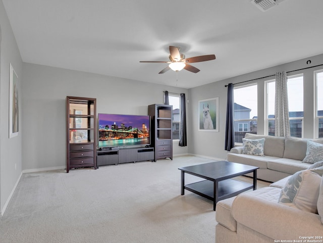 living room featuring a ceiling fan, visible vents, light colored carpet, and baseboards