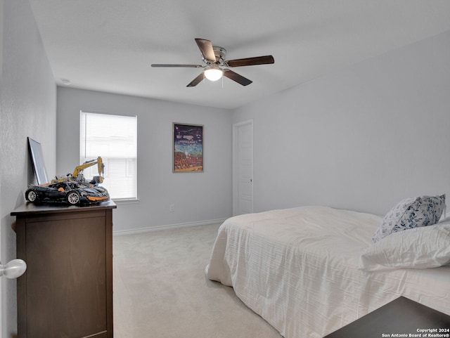 bedroom featuring light colored carpet, a ceiling fan, and baseboards