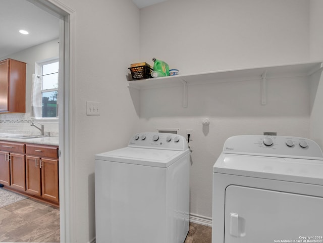 washroom featuring separate washer and dryer, laundry area, and a sink