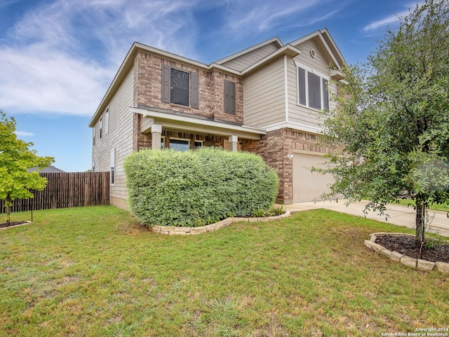 traditional-style house with brick siding, fence, driveway, a front yard, and an attached garage