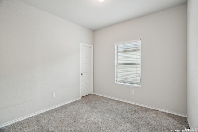 spare room featuring carpet flooring and baseboards