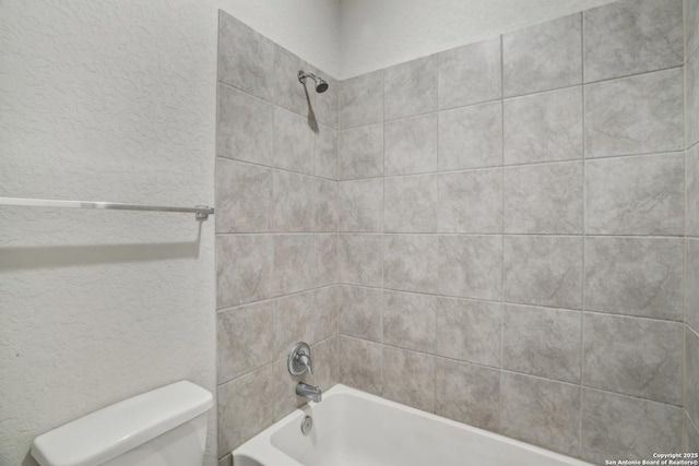 bathroom with toilet, a textured wall, and  shower combination