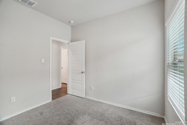 unfurnished room with visible vents, a healthy amount of sunlight, carpet flooring, and baseboards