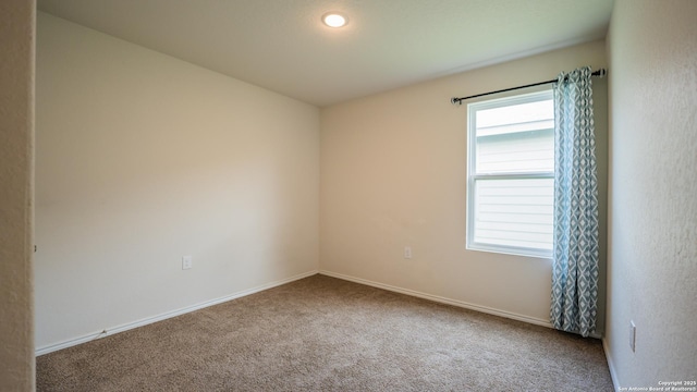 unfurnished room featuring carpet and baseboards