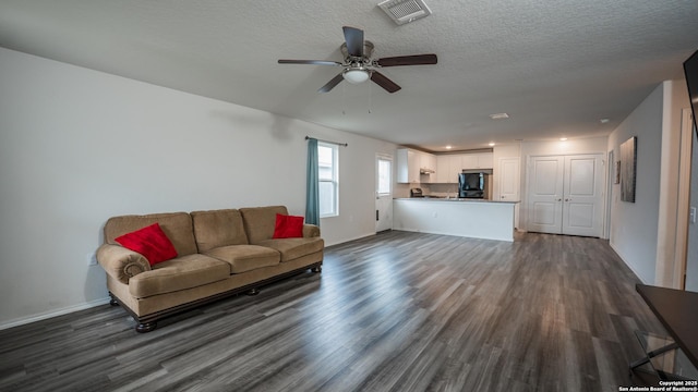 living area featuring ceiling fan, visible vents, baseboards, a textured ceiling, and dark wood finished floors