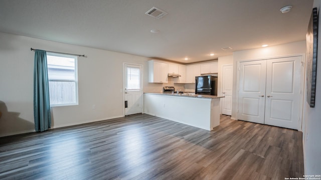 kitchen featuring dark wood-type flooring, visible vents, a peninsula, white cabinets, and freestanding refrigerator