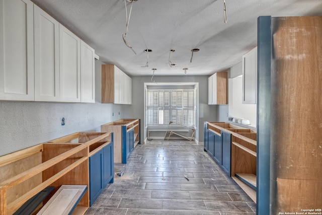 kitchen featuring dark wood-type flooring, white cabinetry, blue cabinets, and a textured ceiling