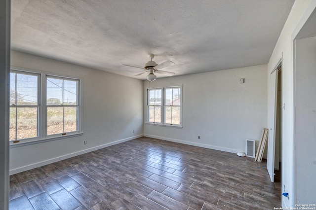 empty room featuring a ceiling fan, dark wood-style flooring, baseboards, and visible vents