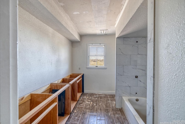 full bath featuring a tub to relax in, hardwood / wood-style floors, and a textured wall