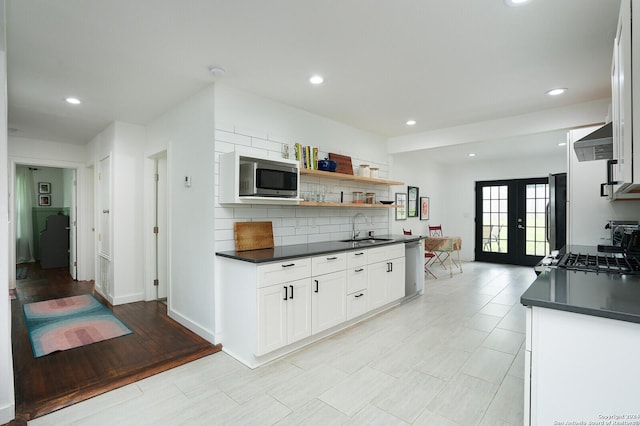 kitchen with decorative backsplash, a sink, appliances with stainless steel finishes, dark countertops, and french doors