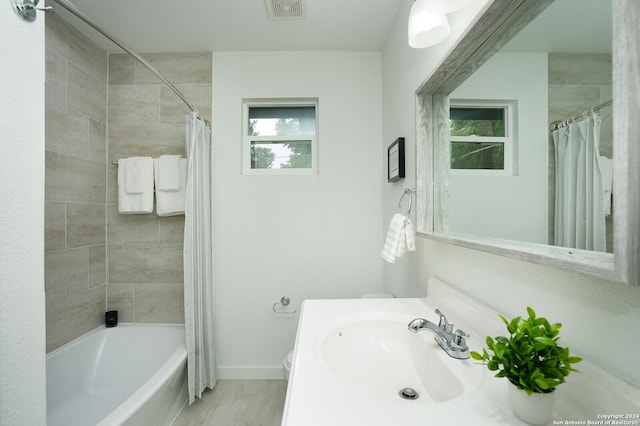 bathroom featuring visible vents, baseboards, toilet, shower / bath combination with curtain, and vanity
