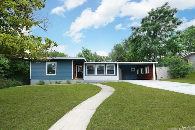 view of front facade featuring driveway, fence, a front yard, and an attached carport