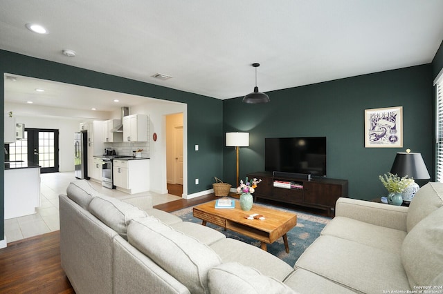 living room featuring an accent wall, visible vents, baseboards, light wood-type flooring, and recessed lighting