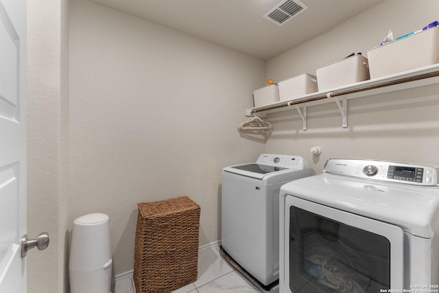clothes washing area with washing machine and dryer, laundry area, marble finish floor, visible vents, and baseboards