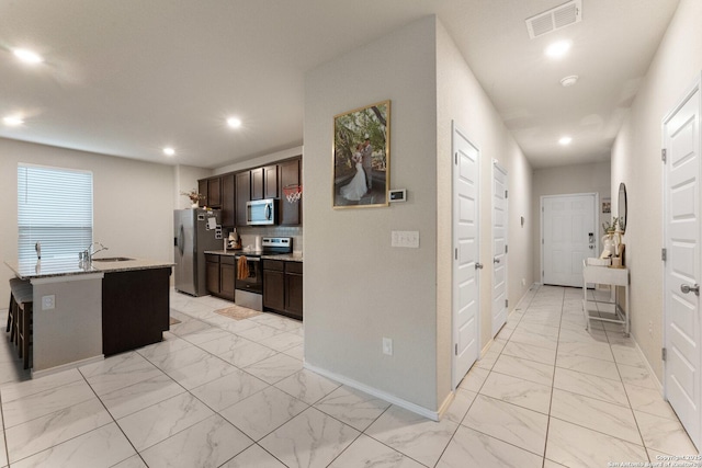 kitchen with recessed lighting, stainless steel appliances, marble finish floor, dark brown cabinets, and baseboards