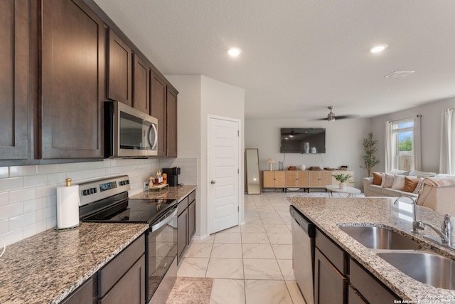 kitchen with a sink, dark brown cabinetry, marble finish floor, appliances with stainless steel finishes, and open floor plan