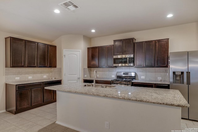 kitchen featuring a sink, stainless steel appliances, visible vents, backsplash, and dark brown cabinets