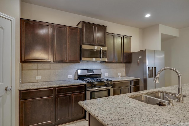 kitchen featuring dark brown cabinets, backsplash, appliances with stainless steel finishes, and a sink