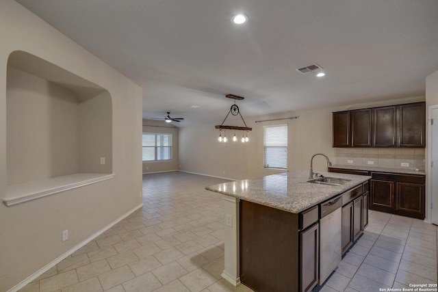 kitchen featuring stainless steel dishwasher, a sink, visible vents, dark brown cabinetry, and backsplash