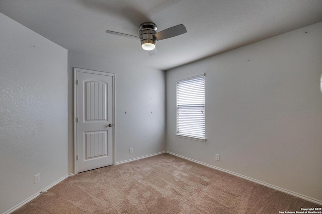 unfurnished room featuring a ceiling fan, light carpet, and baseboards