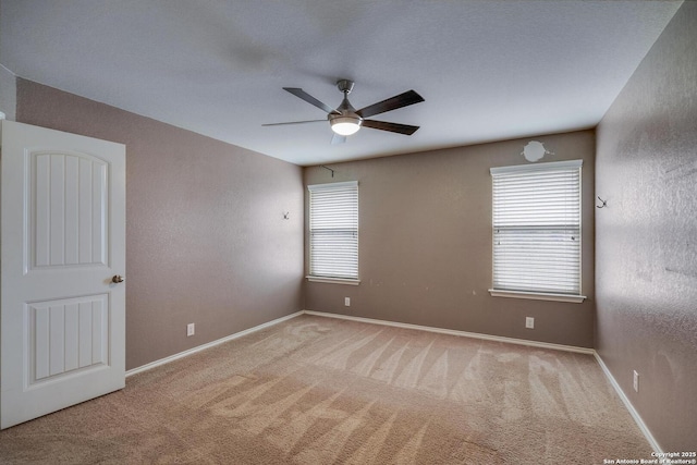 spare room featuring a ceiling fan, carpet floors, and baseboards