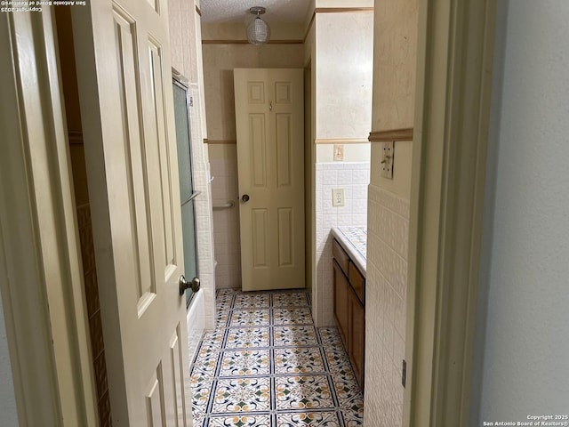 10955 Wurzbach Unit 203, San Antonio, TX 78230 - bathroom featuring vanity, tile walls, tile patterned floors, and combined bath / shower with glass door
