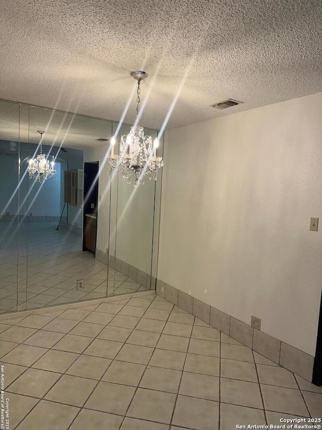 10955 Wurzbach Unit 203, San Antonio, TX 78230 - tiled empty room with visible vents, a notable chandelier, and a textured ceiling