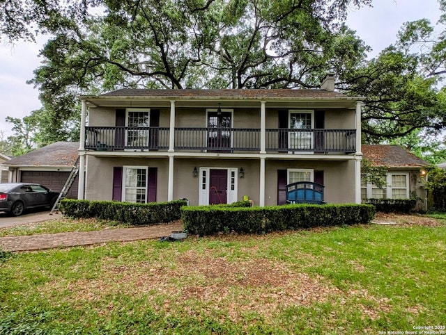 2465 Gladys St, Beaumont, TX 77702 - view of front of house with a front lawn, a chimney, stucco siding, and a balcony