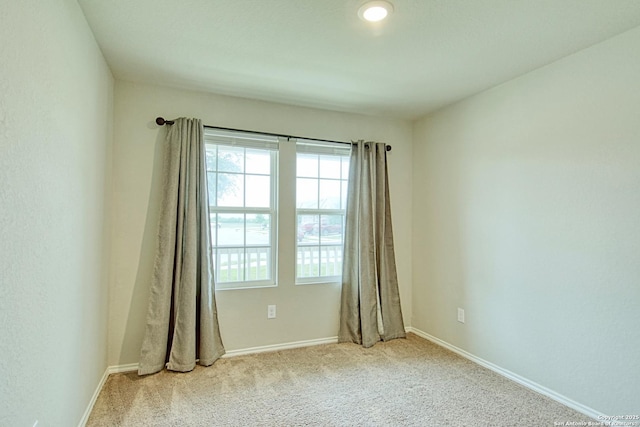 carpeted spare room with a wealth of natural light and baseboards
