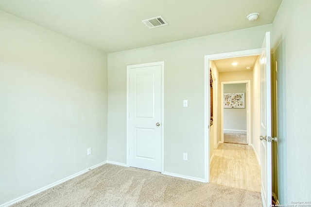 unfurnished bedroom with light colored carpet, visible vents, and baseboards