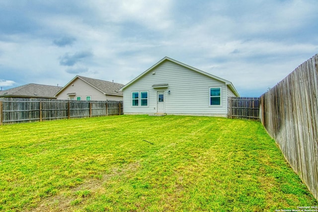 rear view of property with a yard and a fenced backyard