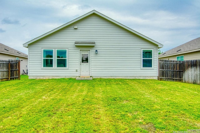 rear view of property featuring a fenced backyard and a yard