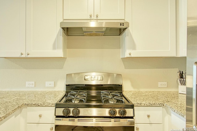 kitchen with light stone counters, stainless steel gas range oven, white cabinets, and under cabinet range hood