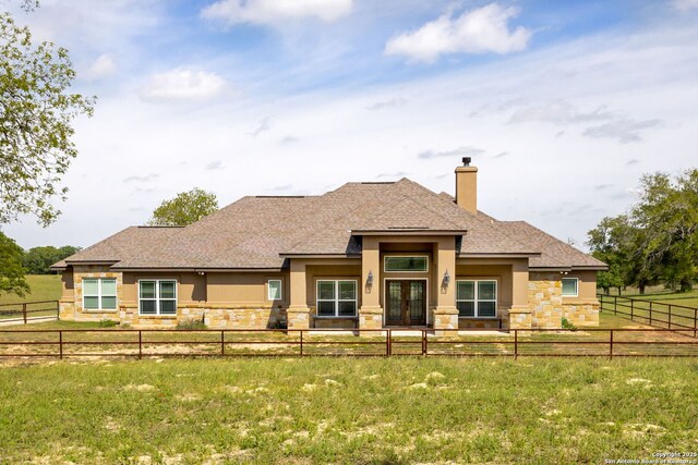 rear view of house with stone siding, stucco siding, and french doors