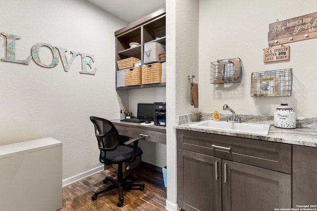 office space with dark wood-style floors, baseboards, built in desk, and a sink