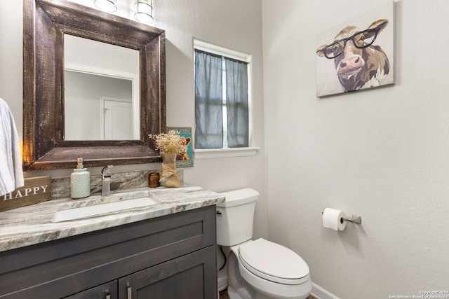 bathroom with baseboards, toilet, and vanity