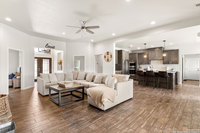 living room with dark wood-style flooring, visible vents, ceiling fan, and recessed lighting