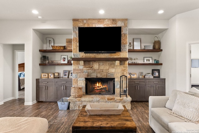 living area featuring dark wood-type flooring, recessed lighting, a stone fireplace, and baseboards