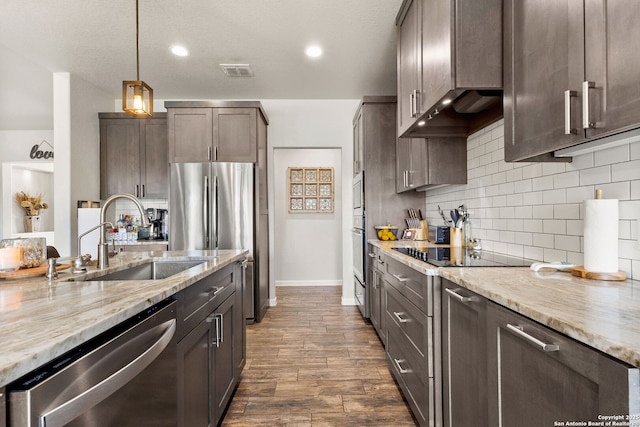 kitchen with light stone counters, a sink, visible vents, stainless steel appliances, and dark brown cabinetry